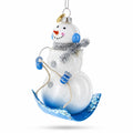 Snowman Riding a Sled Glass Christmas Ornament