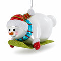 Snowman Gleefully Riding a Sled Glass Christmas Ornament